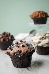 Muffin Auswahl mit Blaubeeren, Walnuss, Haselnuss und Weiße Schokolade mit Milch und Zucker für Kaffeepause auf Marmor Tisch und Grün Hintergrund