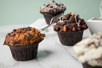 Muffin Auswahl mit Blaubeeren, Walnuss, Haselnuss und Weiße Schokolade mit Milch und Zucker für Kaffeepause auf Marmor Tisch und Grün Hintergrund