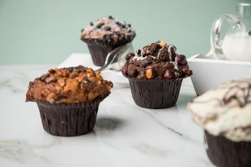 Muffin Auswahl mit Blaubeeren, Walnuss, Haselnuss und Weiße Schokolade mit Milch und Zucker für Kaffeepause auf Marmor Tisch und Grün Hintergrund