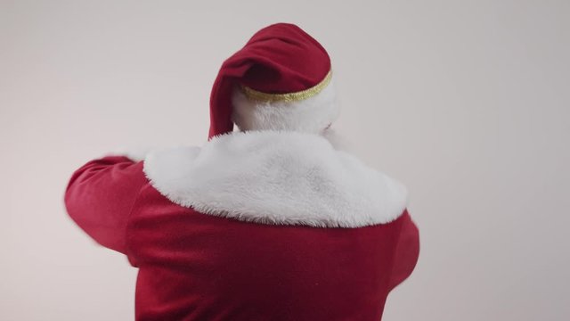 Santa Claus on his back on yellow background. Santa Claus from behind, looking back. Dancing.