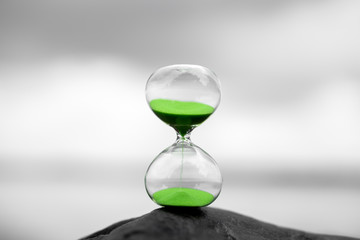 green hourglass against a blurred background in nature