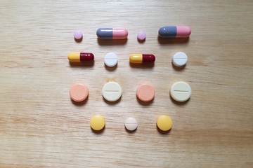 Pills arranged in rows on a wooden table