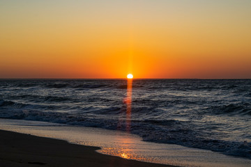 Fototapeta premium Sunrise over the Black sea, waves on the sandy beach.