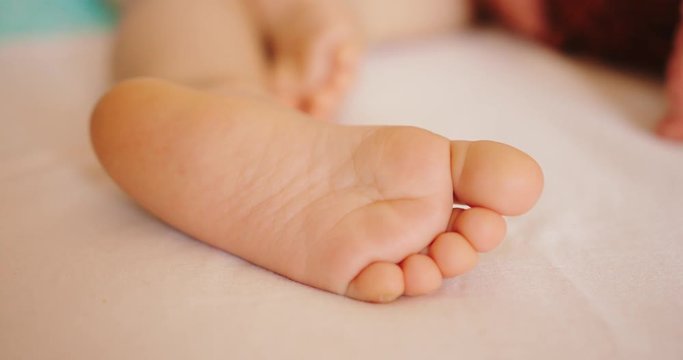 Baby foot lying on the sheet indoors during the daytime