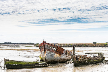 The Noirmoutier boats cemetery. A group of wrecks of old wooden fishing boats are piled on the mud.