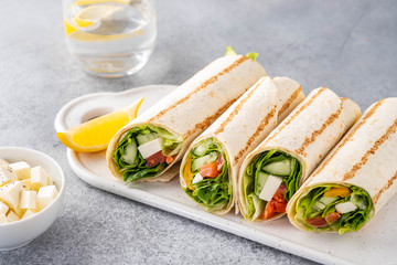 Wrap sandwich, roll with fish salmon, vegetables and cheese. Grey background. Close up.