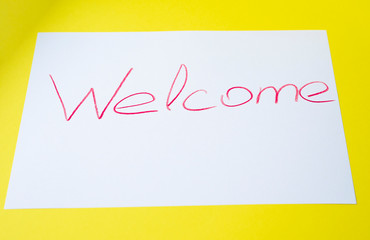 The inscription welcome on white paper on a yellow background.