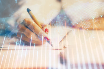 Double exposure of woman's hands making notes with forex graph hologram. Concept stock market analysis.