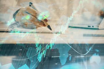 Double exposure of woman's hands making notes with forex graph hologram. Concept technical analysis.