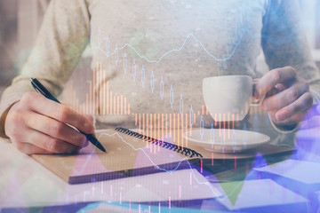 Forex chart hologram on hand taking notes background. Concept of analysis. Double exposure