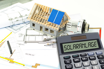 Solar energy cells on a blueprint or construction plan with calculator showing the word solar plant