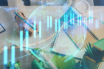 Financial forex graph displayed on hands taking notes background. Concept of research. Multi exposure