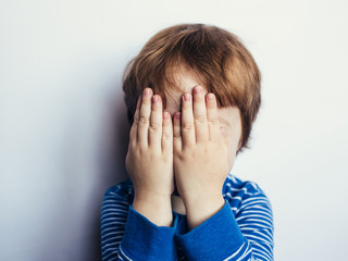 sad little boy covered his face with his hands, child psychology and emotions