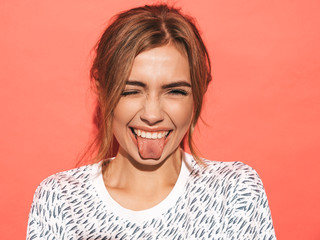 Closeup portrait of young beautiful sexy smiling hipster woman.Trendy positive girl going crazy.Model isolated on pink wall.Shows her tongue
