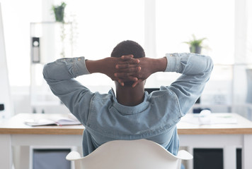 African american worker resting at workplace, leaning back on chair