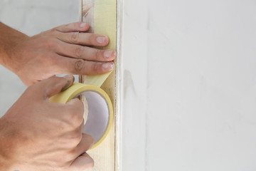 Man putting tape on the wall. The simple step for the quick and easy painting process. Renovation...