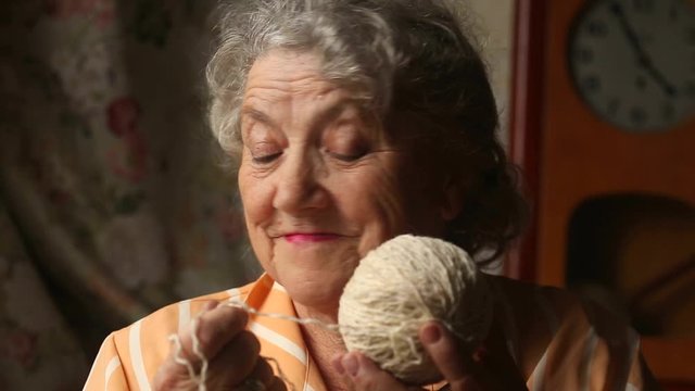 Elderly smile woman with white yarn wool ball