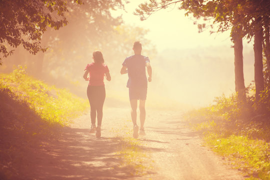 young couple jogging on sunny day at nature