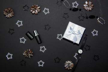 Beautiful Christmas composition on a black background with a Christmas gift box, cosmetics and Christmas decorations. View from above. Copy space