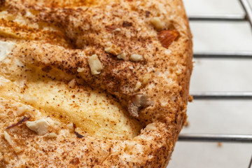 Sponge cake with apples, crushed walnuts and cinnamon lies on a round metal stand, close-up