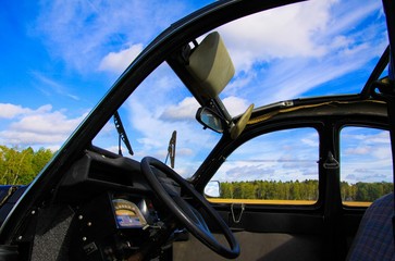 Viersen, Germany - October 12. 2019: View inside classic French cult car 2CV on front seat, dashboard and steering wheel with open folding roof and windows against blue sky