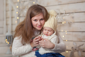 Portrait of a cute toddler girl and her mother in a winter white interior. Mother hugging her daughter. The concept of the New Year and Christmas.