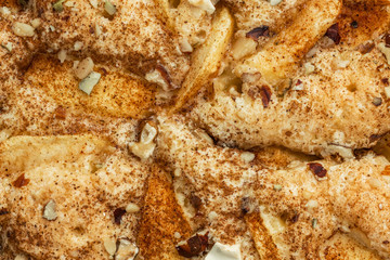 Background in the form of a sponge cake with apples, crushed walnuts and cinnamon, close-up