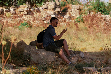 Tourist young man is looking at the map in his smartphone. Summer and travel. Orienteering using gadgets and new technologies.
