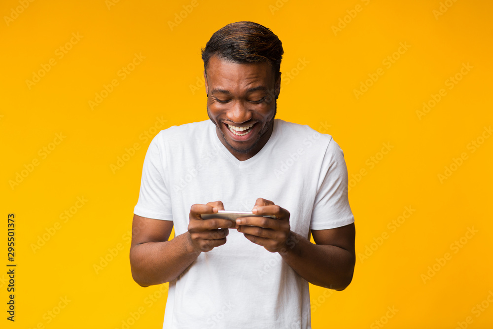 Canvas Prints Excited Black Man Using Cellphone Playing Games, Studio Shot