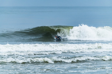 Bodyboarder surfing ocean wave on a sunny day.