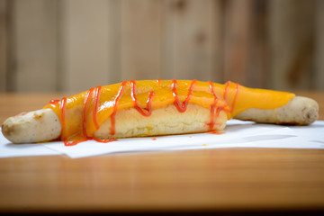 Jumbo hotdog with cheese and ketchup in a brioche roll