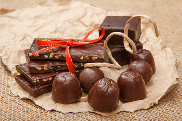 Chocolate bars with nuts and chocolate candies on pack paper.