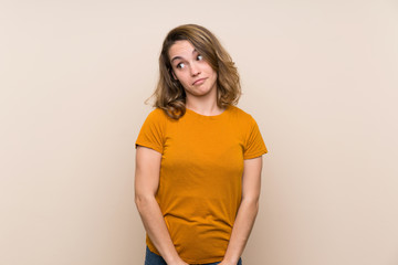 Young blonde girl over isolated background making doubts gesture looking side