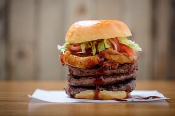 Triple stack beef burger with onion rings, salad and bbq sauce
