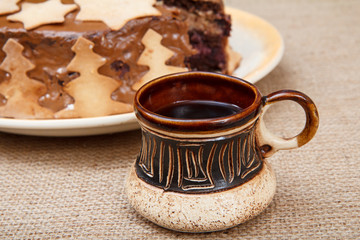 Chocolate cake on the plate and cup of coffee on the sackcloth