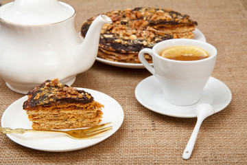 Cup of tea, porcelain teapot and homemade chocolate puff cake on white plate