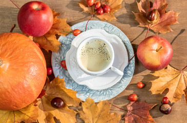 Autumn, fall leaves, a hot steaming cup of coffee, pumpkin and a warm sweater on a wooden table background.