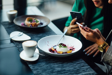 Two friends, sisters, attractive girls eat dessert in a restaurant, a cafeteria, drink from glass cups, photo food, close up photo.