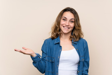 Young blonde woman over isolated background holding copyspace imaginary on the palm