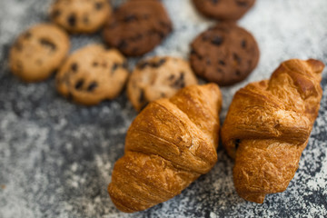 Macro closeup display of plain butter croissant with cookies crescent pastries in bakery for breakfast.