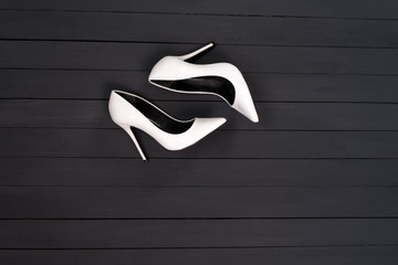 White female shoes on a black wooden background. Fashion concept