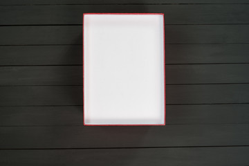Empty open white cardboard box on black wooden background. Top view