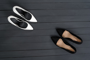 Black and white female shoes on a black wooden background. Fashion concept