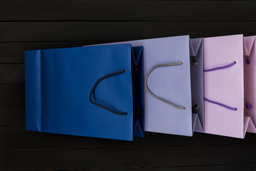 Paper multi-colored shopping bags on black wooden background. Top view.