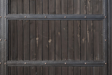Brown wooden gate with forged metal stripes. Backgrounds and textures. Close up