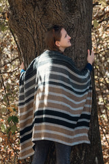 Young woman hugging a tree. Unity with nature, autumn forest