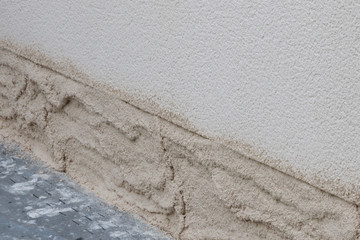 Travaux de réparation sur une maison : ravallement du bas d'une façade