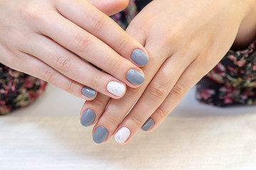Obraz na płótnie Canvas Stylish trendy female manicure. Beautiful young womans hands. gray and white nail polish