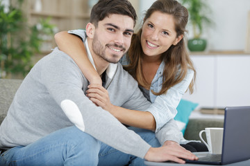 Obraz premium embracing couple using laptop at home