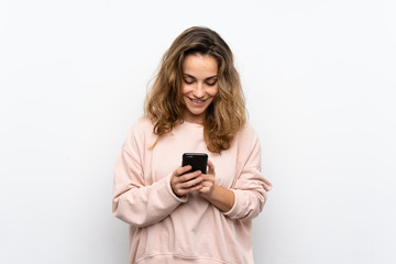 Young blonde woman sending a message or email with the mobile